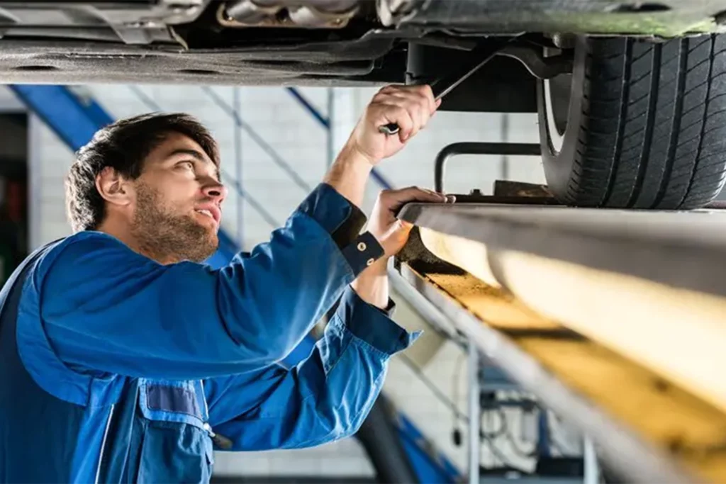 Service mechanic under commercial vehicle in below-ground service bay